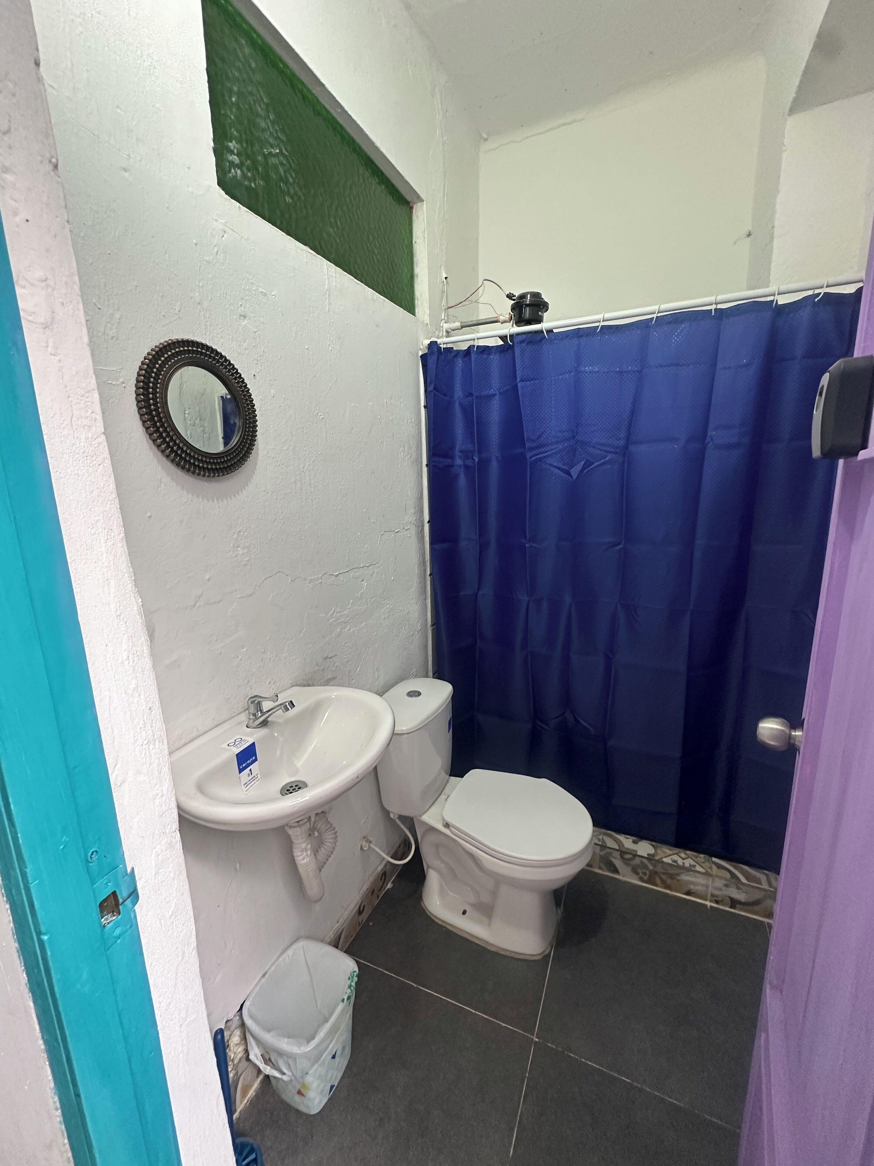 A small bathroom with a white sink, toilet, and blue shower curtain.