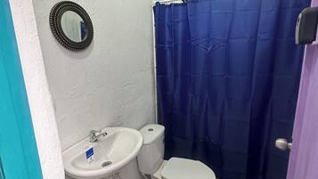 A small bathroom with a white sink, toilet, and blue shower curtain.