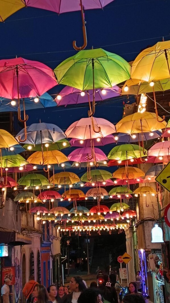 A street scene with colorful umbrellas hanging overhead, creating a vibrant canopy.