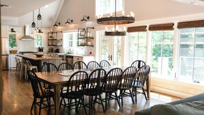 Een ruime keuken met een houten bar, moderne apparaten en veel natuurlijk licht door grote ramen.