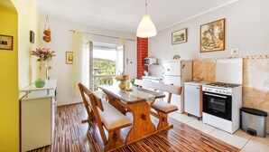 Een keuken met een eettafel, stoelen, een fornuis, een magnetron en een koelkast.
