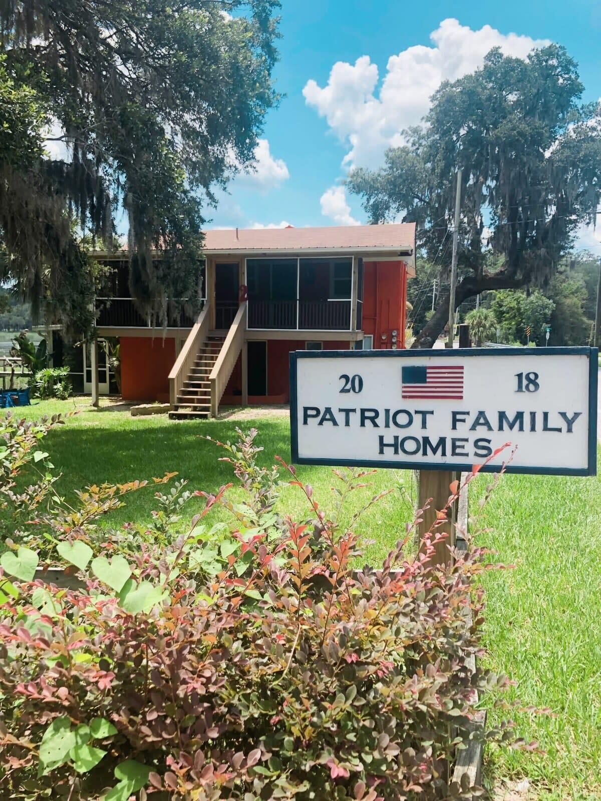 A sign for Patriot Family Homes with a two-story building in the background.