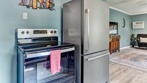 A kitchen with a stainless steel refrigerator, a black oven, and a wall-mounted wine rack. - Dock&Volleyball! Near Downtown - Canary Cottage (Savannah)