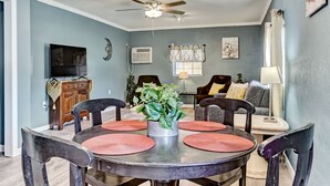 A dining area with a round table, four chairs, a ceiling fan, and a potted plant. - Dock&Volleyball! Near Downtown - Canary Cottage (Savannah)