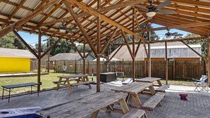 An outdoor patio area with wooden picnic tables and a covered roof structure. - Dock&Volleyball! Near Downtown - Canary Cottage (Savannah)