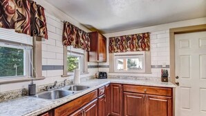 Una cocina con armarios de madera, encimeras de granito y adornos de ventana estampados.
