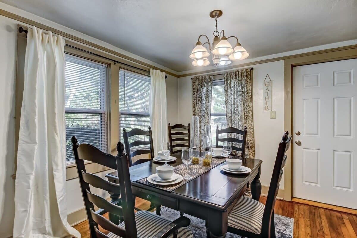 A dining room with a dark wooden table set for four, surrounded by chairs with striped cushions.