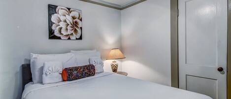 Une chambre à coucher avec un lit, des oreillers, une lampe et une porte.