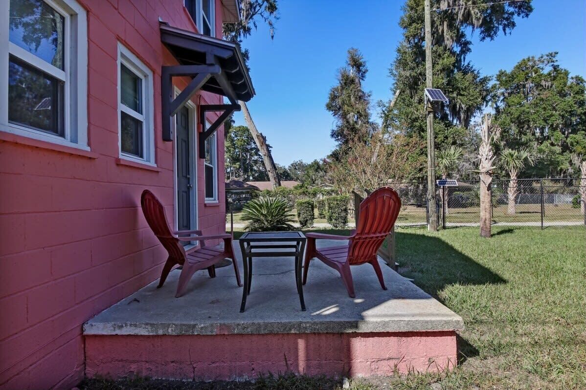 Ein rotes Haus mit Veranda, zwei Stühlen und einem kleinen Tisch.