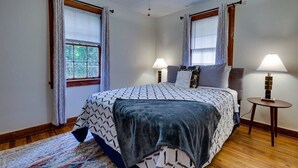 Une chambre à coucher avec un lit, deux lampes de chevet, un tapis et des fenêtres avec des rideaux.