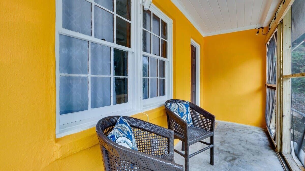 A porch with two wicker chairs and a window.