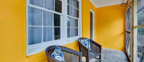 A porch with two wicker chairs and a window.