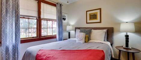 A neatly made bed with a red blanket, two bedside lamps, and a framed picture on the wall.