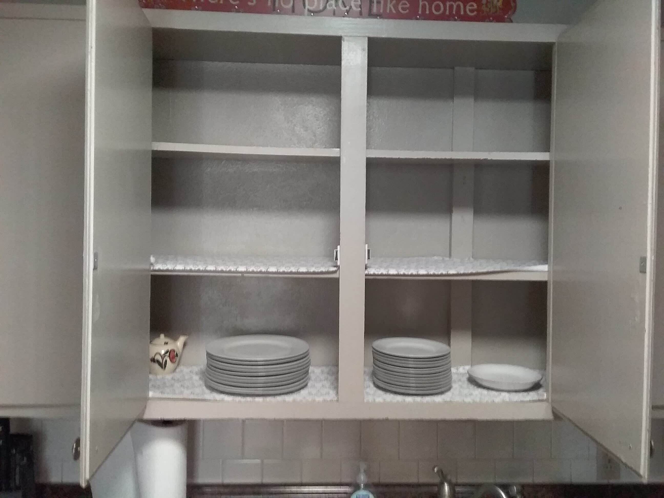 Een keukenkast met meerdere planken, waarvan sommigen gevuld zijn met stapels borden.