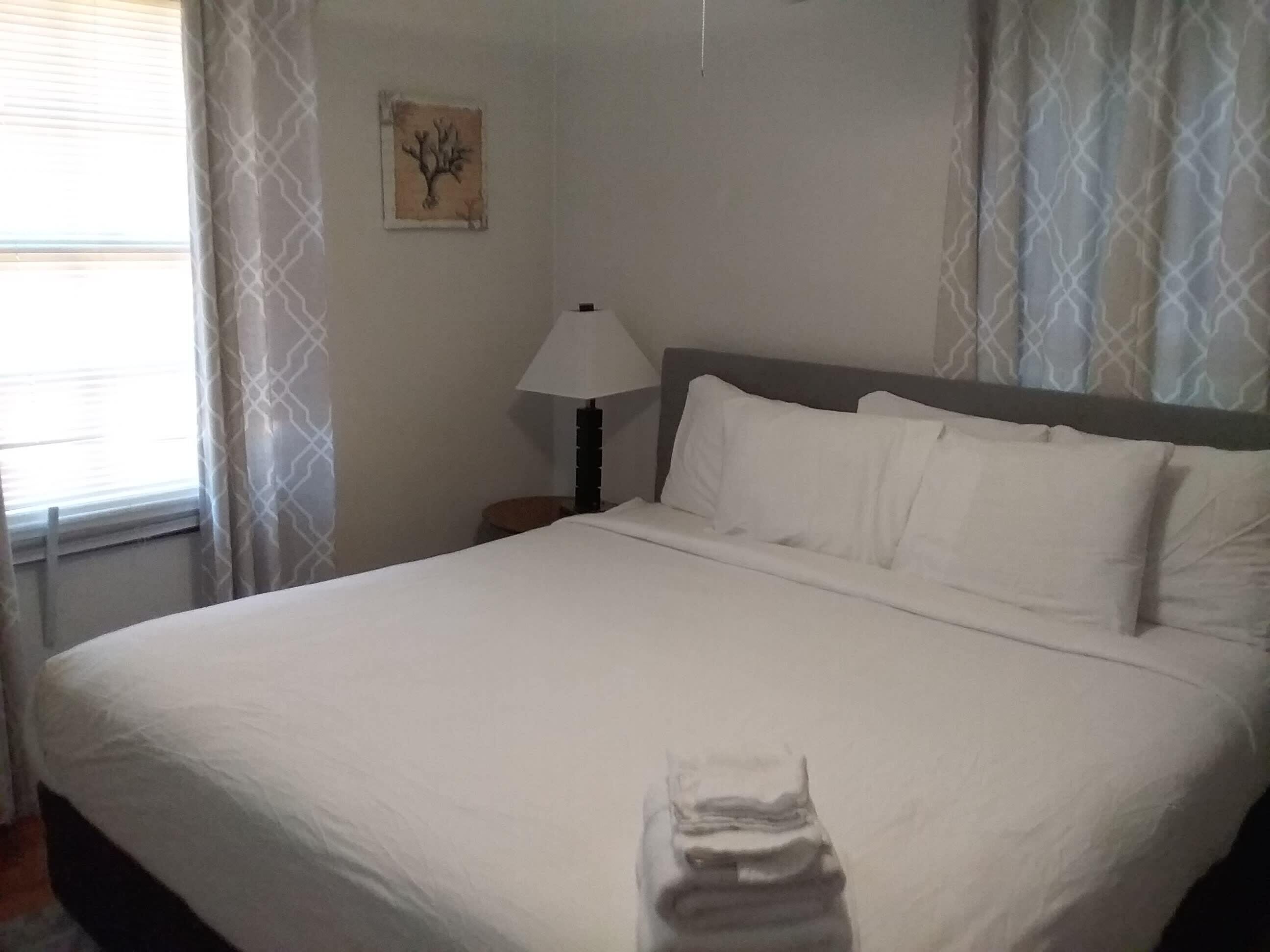 A neatly made bed with white linens in a hotel room.