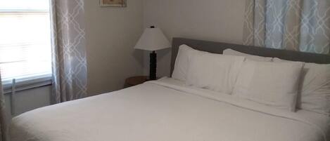 A neatly made bed with white linens in a hotel room.