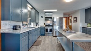 A modern kitchen with grey cabinets, stainless steel appliances, and a marble countertop. - Dock&Volleyball! Near Downtown - Blue & Turquoise! (Savannah)
