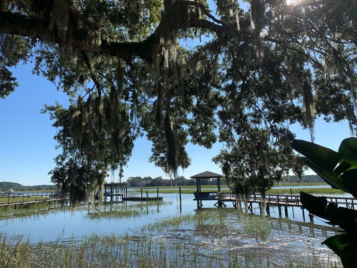 Un parco con un gazebo, un molo di legno e uno specchio d'acqua.