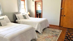 A bedroom with two beds, a patterned rug, and a wooden floor. - Dock&Volleyball! Near Downtown - Totally Turquoise (Savannah)