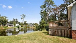 A residential property with a pond, a wooden deck, and a grassy yard. - Marshside Home with Deck & Pond Access Near Tybee (Savannah)