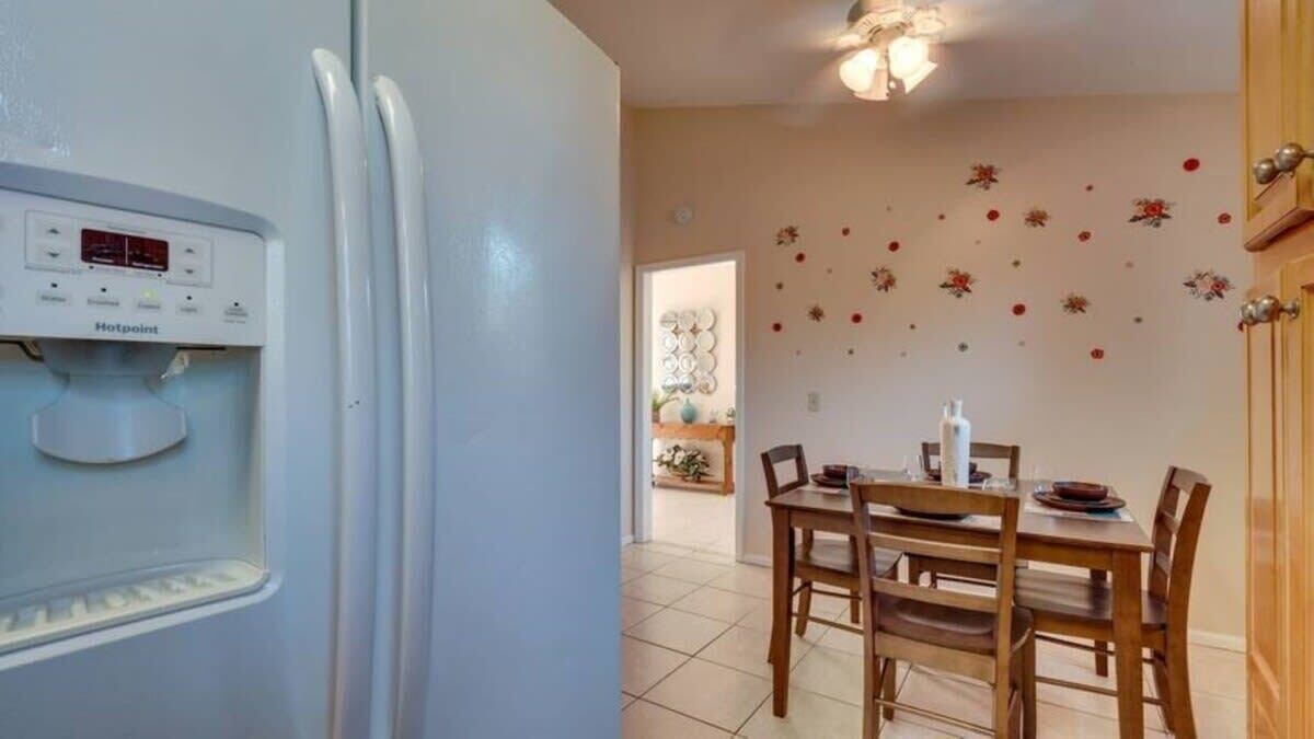 A kitchen with a built-in refrigerator, a dining table with chairs, and a wall decorated with floral decals.