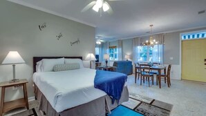 A hotel room with a bed, bedside tables, a desk, and a dining area.