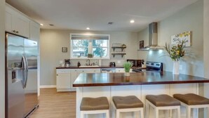A modern kitchen with a central island, stainless steel appliances, and a large window providing natural light.