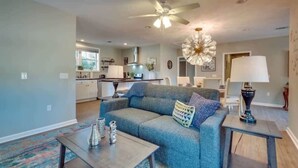 A modern living room with a sofa, coffee table, and a dining area with a lamp.