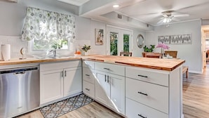 Une cuisine moderne avec des meubles blancs, un plan de travail en bois et un lave-vaisselle.