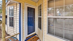 A yellow house with a blue door, a welcome mat, and a window with a sign. - Fenced Yard, Patio & BBQ · Historic District Area (Savannah)