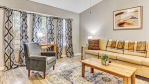 A living room with a sofa, armchair, coffee table, and patterned curtains. - Fenced Yard, Patio & BBQ · Historic District Area (Savannah)