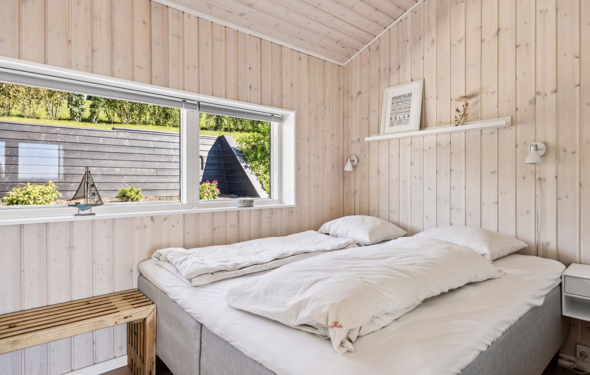 Un dormitorio con una cama, una ventana y una pared de madera.