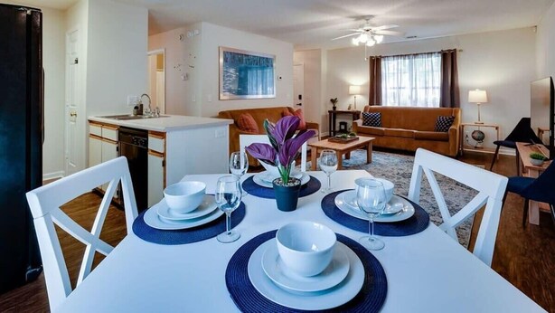 Un coin repas avec une table dressée pour quatre personnes, un canapé, une table basse et un téléviseur en arrière-plan.