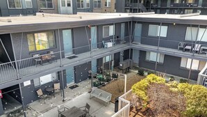 Un edificio de varios pisos con balcones, zonas de estar al aire libre y un pequeño jardín.