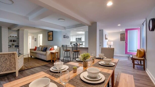 A modern living room with a sofa, dining table set for four, and a kitchen in the background. - Walk to Beach! Flamingle in Fuchsia, Whole House (Tybee Island)