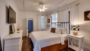 A bedroom with a bed, a bedside table, a dresser, a television, and a ceiling fan. - Walk to Beach! Flamingle in Fuchsia, Whole House (Tybee Island)