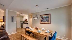 A dining area with a wooden table set for four, a bench, and a pendant light.