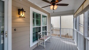 A covered porch with a ceiling fan, a bench, and a wall-mounted lantern.