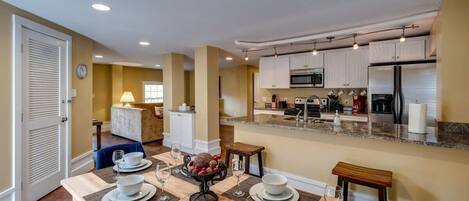 A modern kitchen with white cabinets, stainless steel appliances, and a dining area with a table set for four.