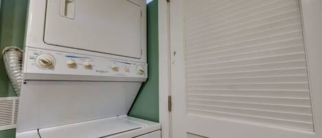 A laundry room with a front-loading washer and dryer, a vent, and a closed door.