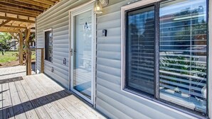 A covered porch with a wooden deck, a sliding glass door, and a large window with blinds. - Beach Vacation! Walkable to Dining&Shopping-Unit A (Tybee Island)