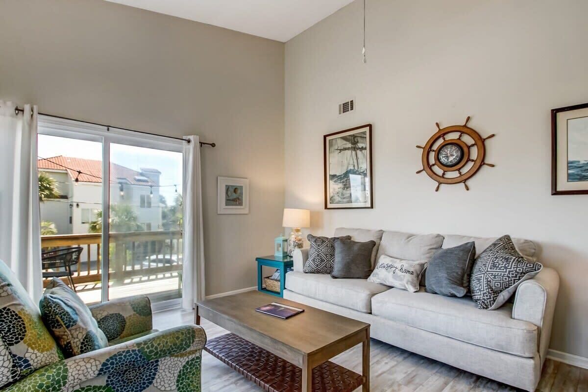 A living room with a sofa, a coffee table, and a view through a sliding glass door.