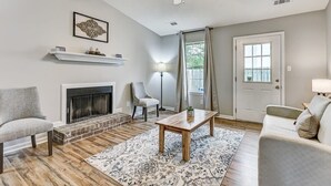 Una sala de estar con chimenea, ventilador de techo, sofá, mesa de centro y alfombra.