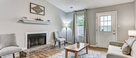 Una sala de estar con chimenea, ventilador de techo, sofá, mesa de centro y alfombra.