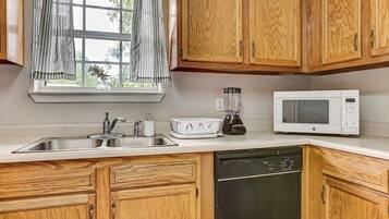 A kitchen with wooden cabinets, a white countertop, a sink, a microwave, and a dishwasher.