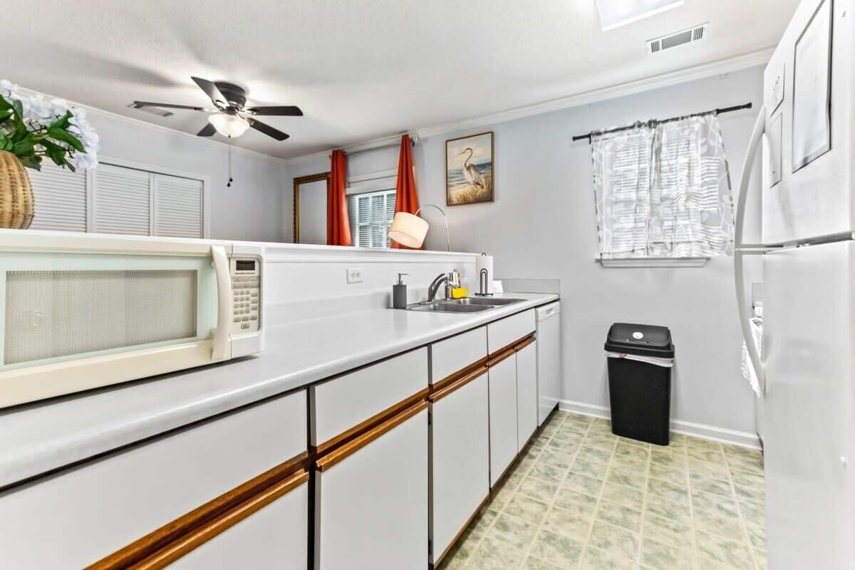 A compact kitchen with a microwave, sink, and a ceiling fan.