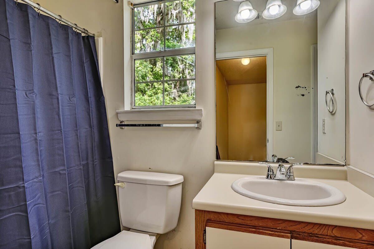 A bathroom with a toilet, sink, and window.