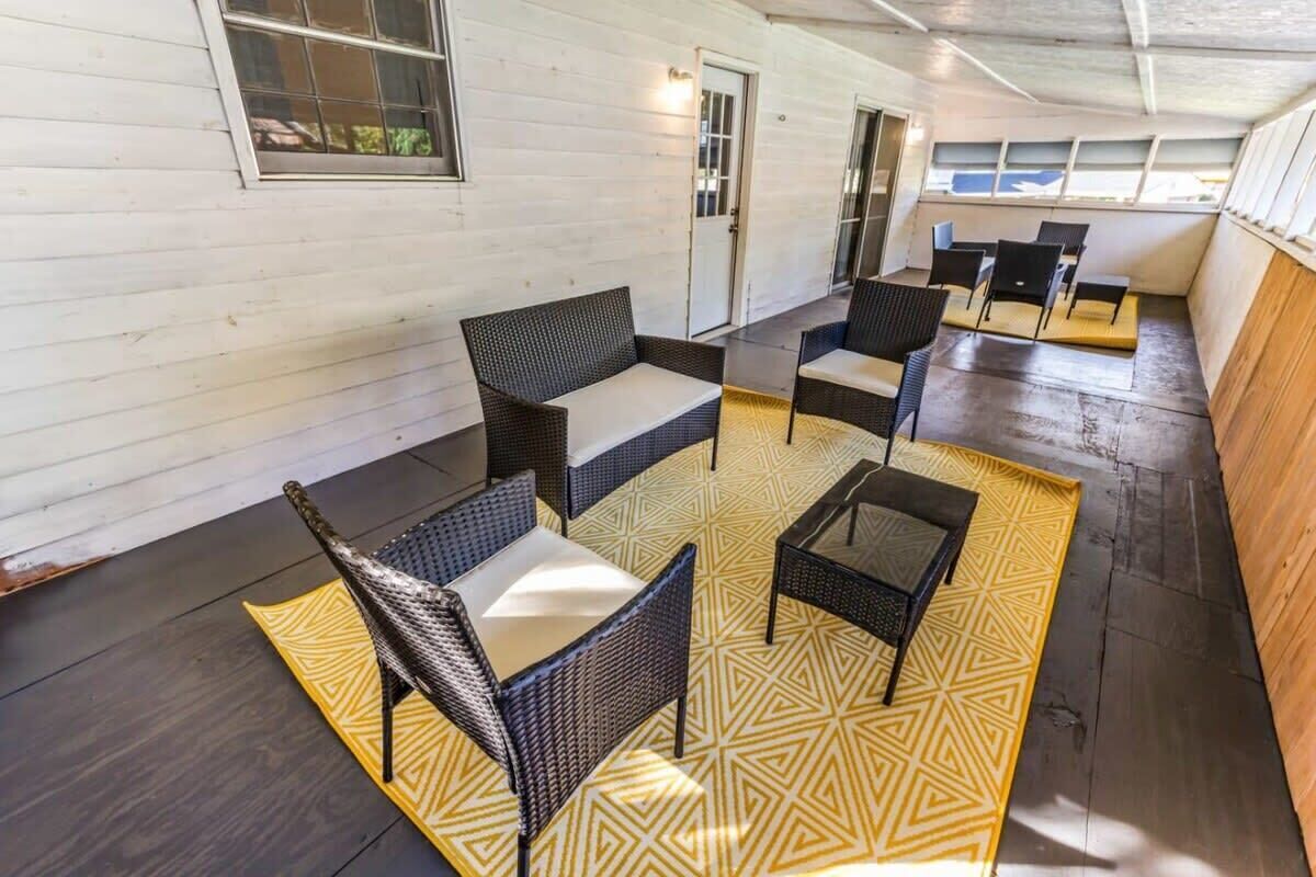 A covered outdoor seating area with wicker furniture and a patterned rug.