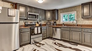 Eine moderne Küche mit Edelstahlgeräten, Granit Arbeitsplatten und dunklen Schränken.