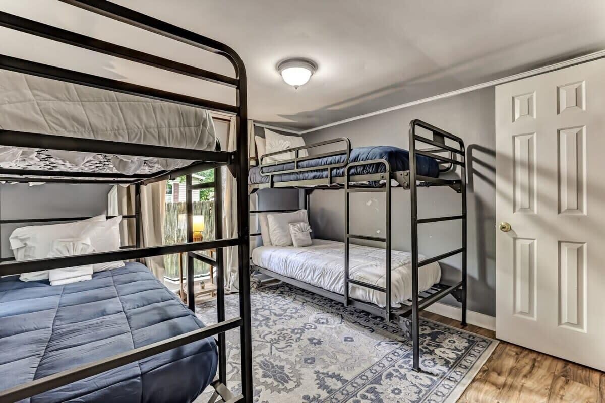 Quarto com beliches, um tapete estampado e uma porta.